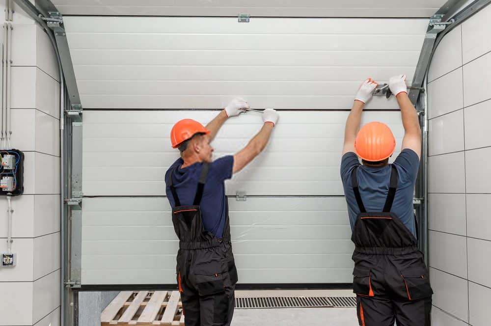 Garage door repair technicians servicing a door